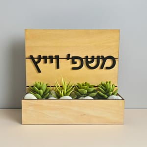 שלט כניסה לבית מעץ עם צמחייה מלאכותית